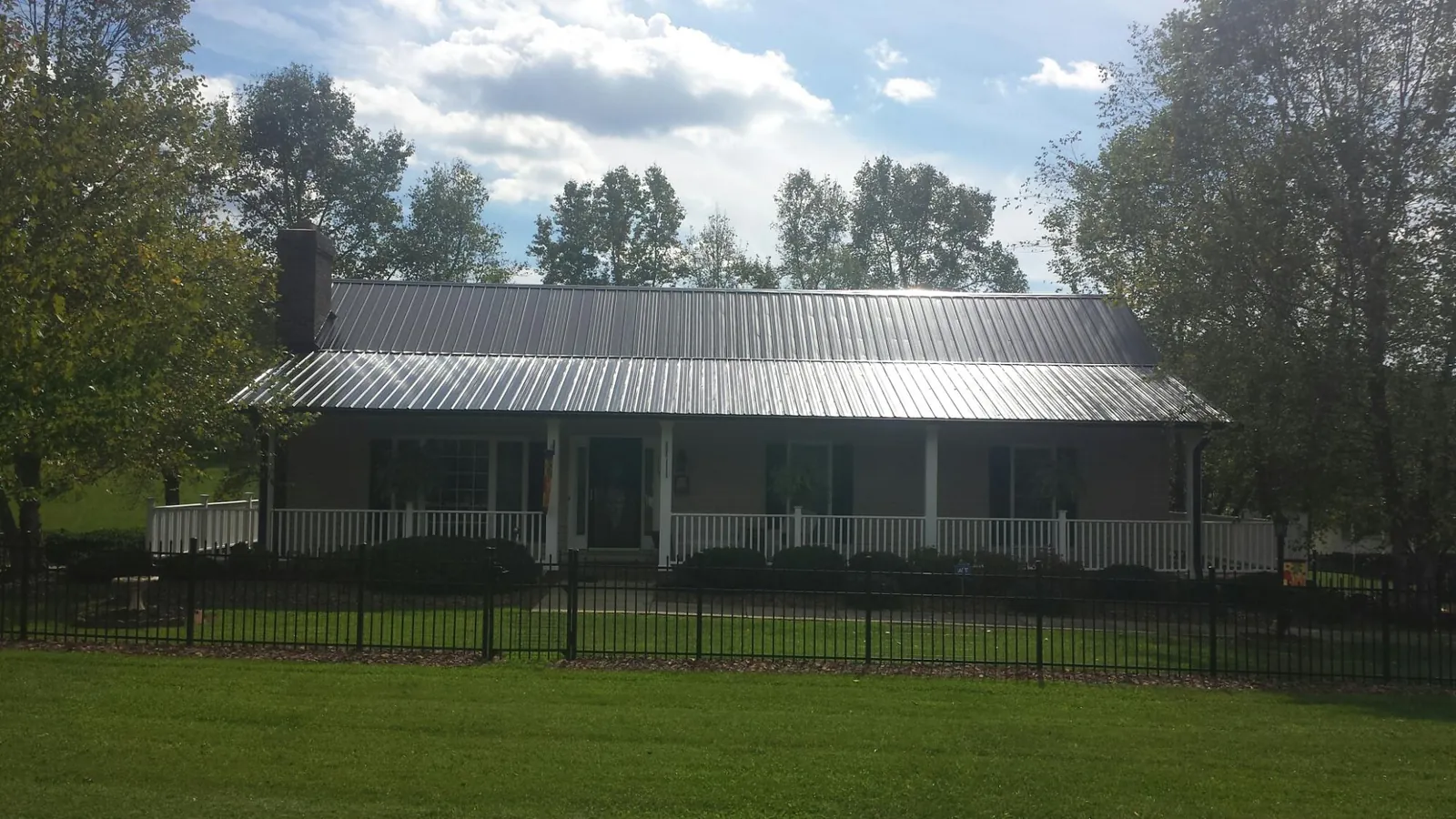 Gray metal roof on a brick ranch with a full width front porch — Gutter Guard Installation work by our crew in California