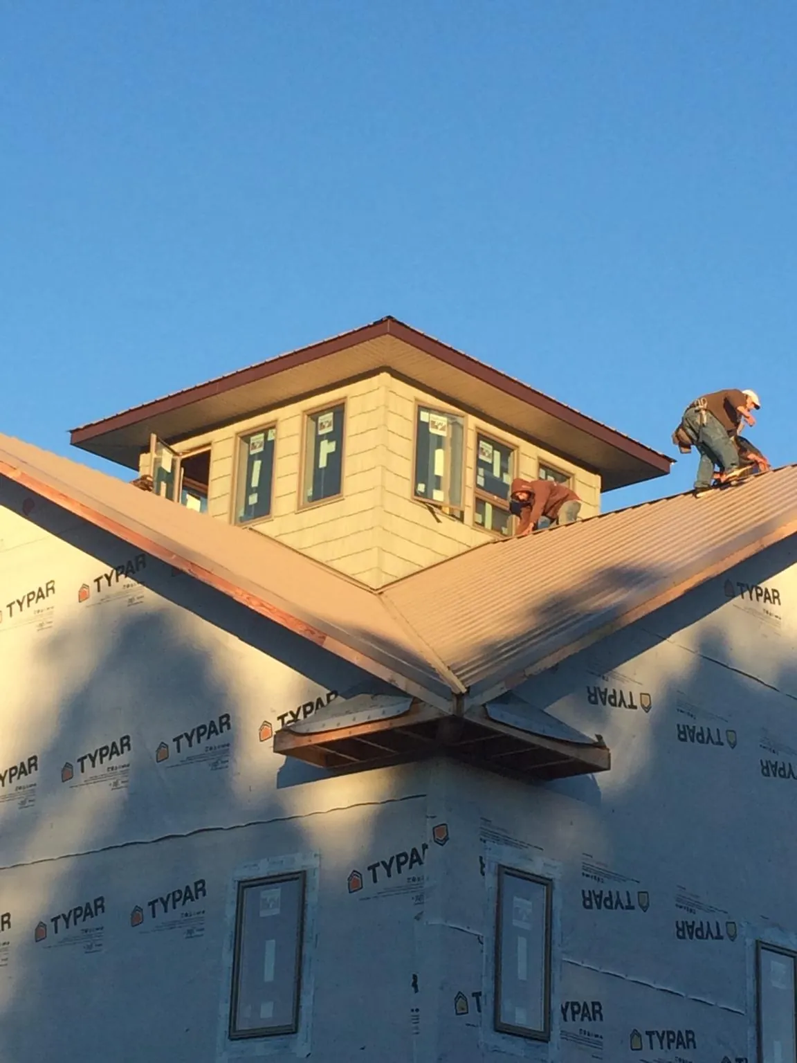 Roofers working around a rooftop cupola on a new metal roof at sunset — Roof Waterproofing in California by Roofing Brothers